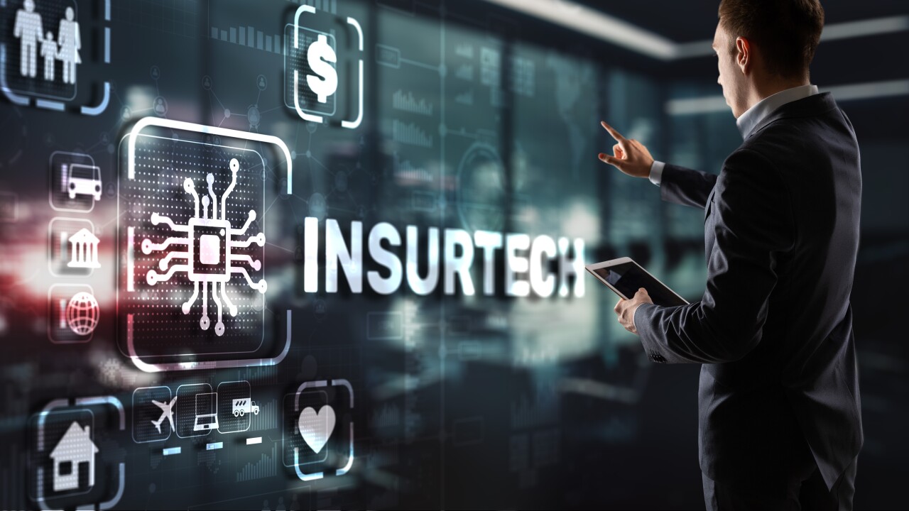 A person using a tablet interacting with a holograph that reads insurtech.