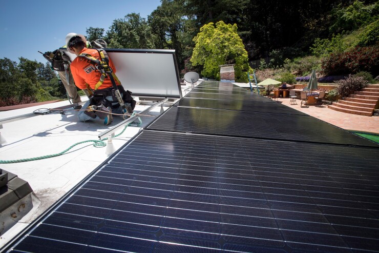 PetersenDean Inc. employees install solar panels on the roof of a home in Lafayette, California, U.S., on Tuesday, May 15, 2018.