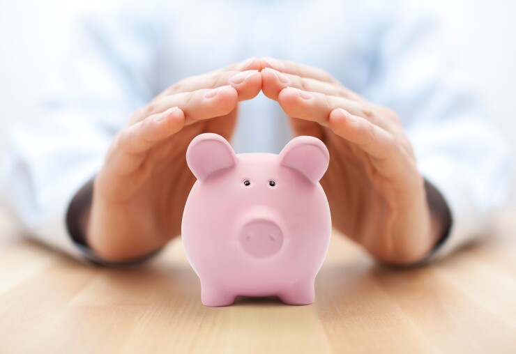 Man's hands protecting piggy bank