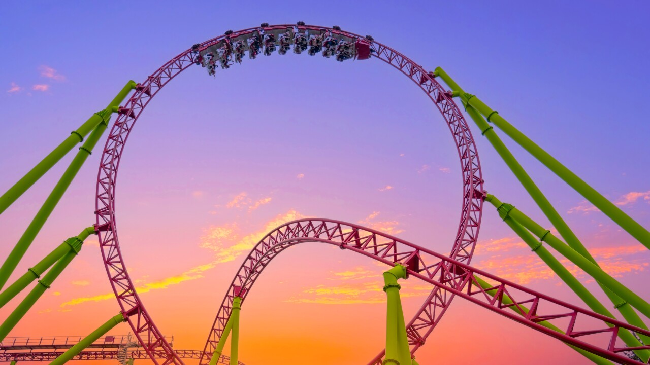 A rollercoaster with the people in an upside-down loop at sunset