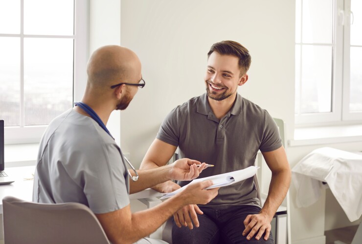 Man speaking with doctor, in doctor's office, smiling
