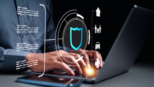 man typing on laptop, behind projection of a shield, auto, home and other logos