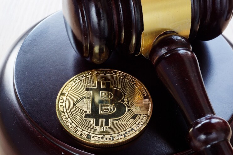 A gold Bitcoin sitting next to a gavel