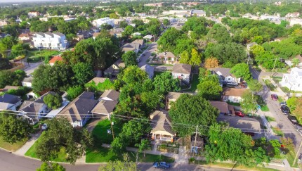 Aerial view of residential houses neighborhood in suburban area of downtown Houston, Texas, US. Tightly packed homes, driveway surrounded with green tree flyover in early morning. Housing development.