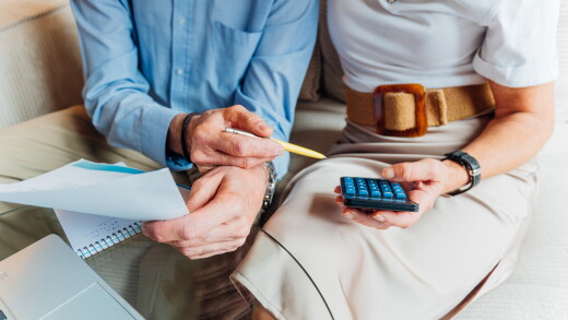 Elderly couple managing household finances and retirement planning, calculating expenses and reviewing bills on a laptop, stressing budget and financial consulting for seniors.