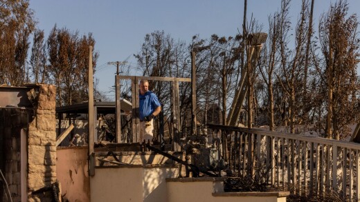 An insurance company employee surveys a home damaged by the Palisades Fire.