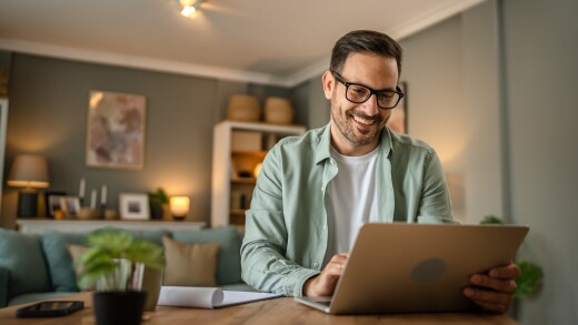 Man sitting at table looking at laptop