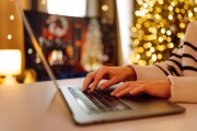 A person typing on a laptop in a cozy setting decorated with warm holiday lights during the festive season. . Business, Freelance, Shopping, education. Online. Cyber security concept