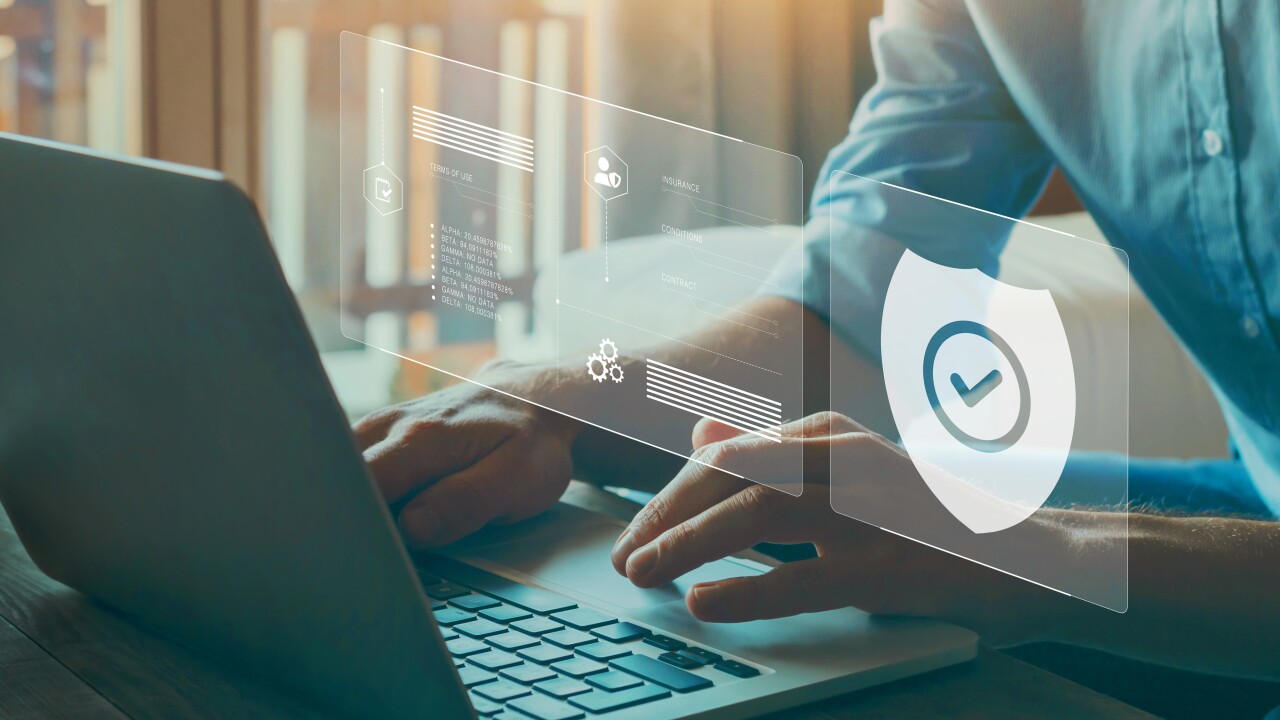 A person using a laptop with a holographic image