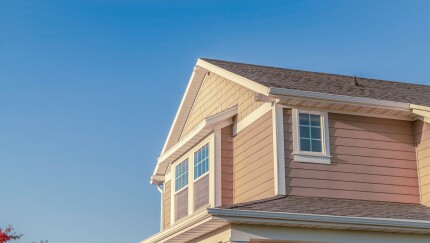 The top floor of a house silhouetted against a blue sky.