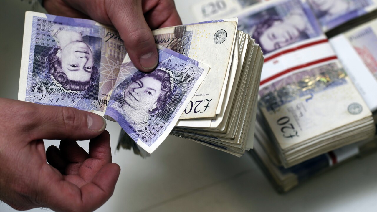An employee manually counts 20 pound sterling banknotes