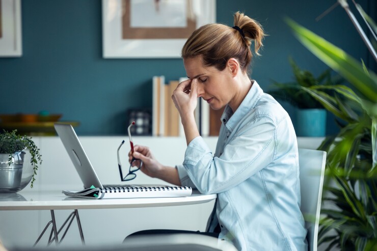 Woman sitting at her desk looking stressed