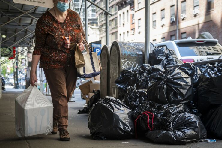 A pedestrian passes piles of garbage on a street in New York on April 24, 2021.