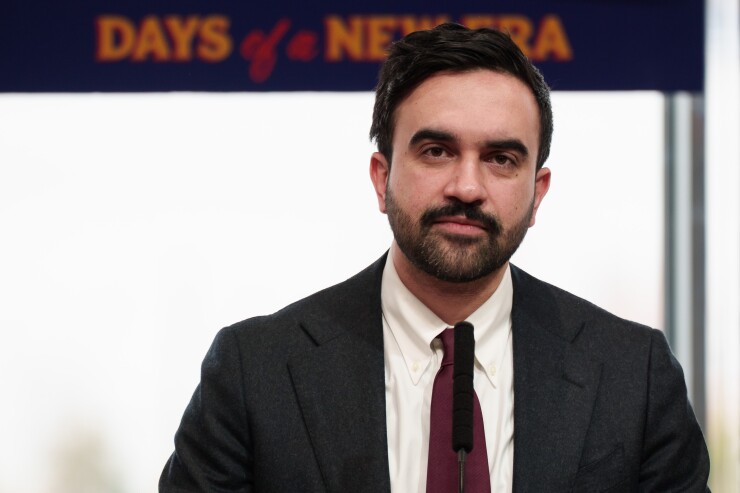 New York Mayor Zohran Mamdani in front of a sign about days of a new era