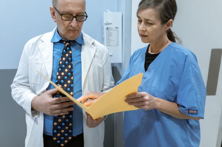 Male doctor in a surgeon's coat and a female doctor or nurse review a patient chart in a hospital