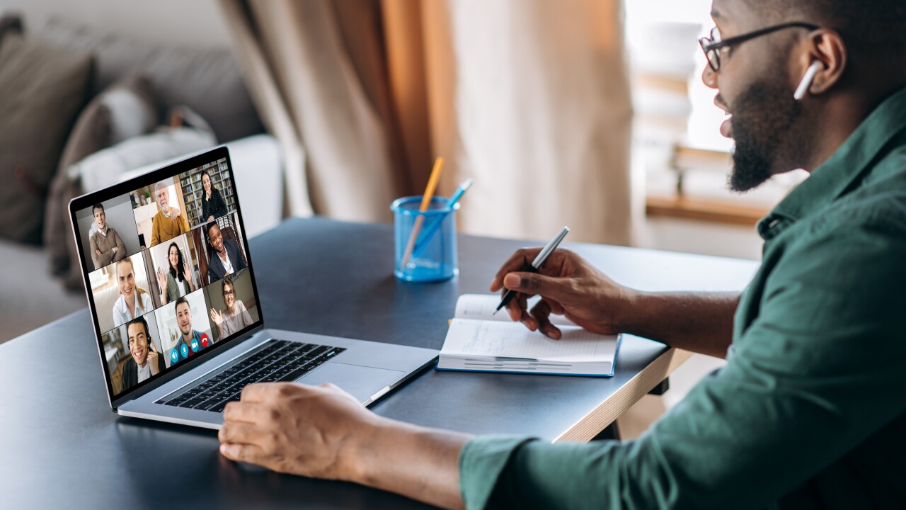 Person on a video call, writing on a desk.