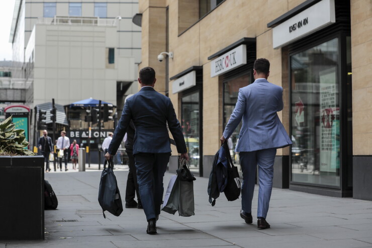 Men carry bags and suit carriers as they leave the offices of Deutsche Bank in London on July 8, 2019.