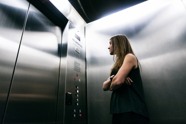Woman standing in an elevator on her way to work