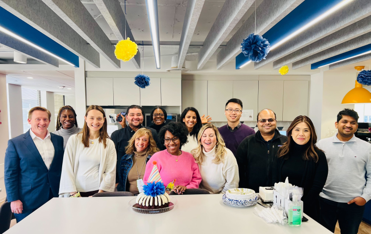 Group of people on MPOWER team stand behind counter with party cake.