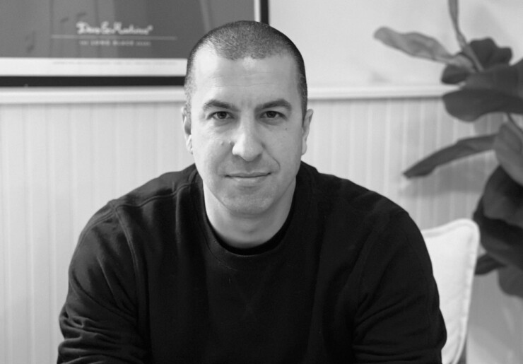 black and white close-up photo of Dakota CEO Ryan Bozarth wearing a black crewneck with a plant behind his left shoulder