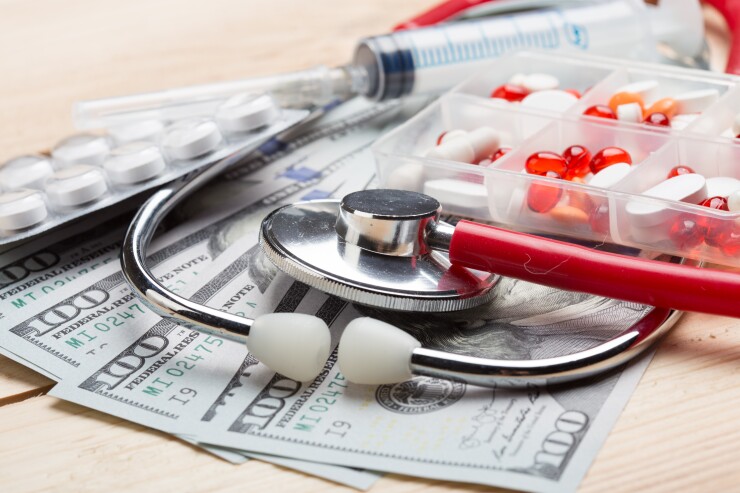 Stock photo of a pill box with medical supplies and cash around it