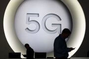 Attendees check their smartphone devices by a 5G sign during the opening day of the Mobile World Congress in Barcelona on Feb. 26, 2018.