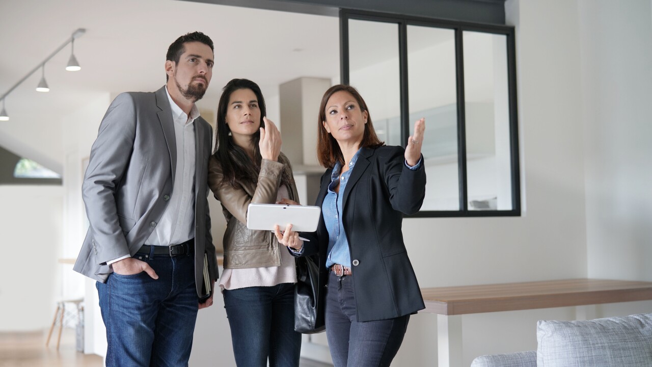 Realtor showing couple a home, gesturing