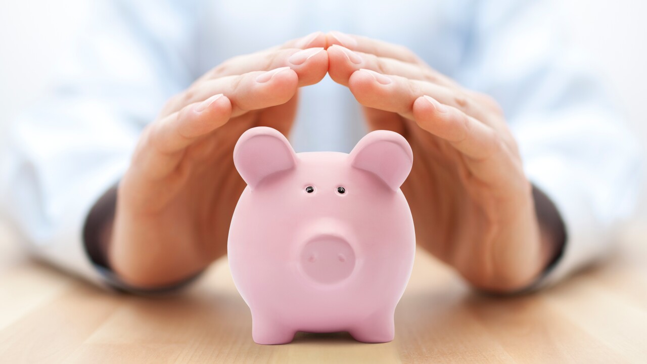 Man's hands protecting piggy bank