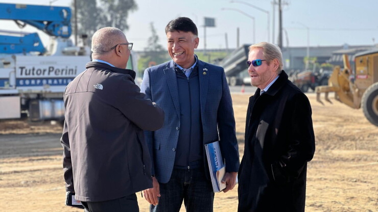 Ian Choudri, center, stands between two other men at a construction site