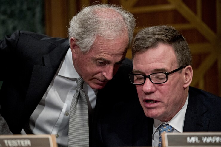Senator Bob Corker, a Republican from Tennessee, left, talks to Senator Mark Warner, a Democrat from Virginia, during a Senate Banking Committee hearing on March 1, 2018.