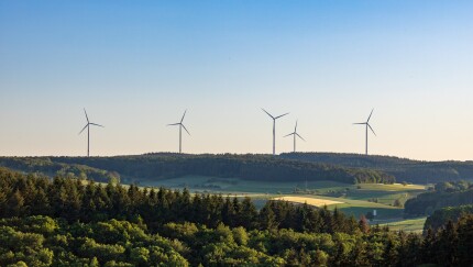 Wind turbines in green field against blue sky in summer in Germany
