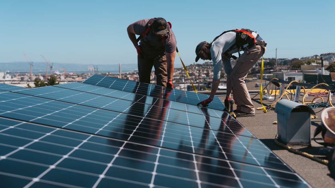 Workers install solar panels at a home in San Francisco.