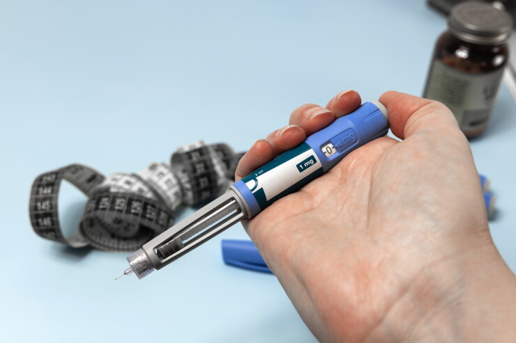 Hand holding Ozempic injection pen for diabetes treatment.