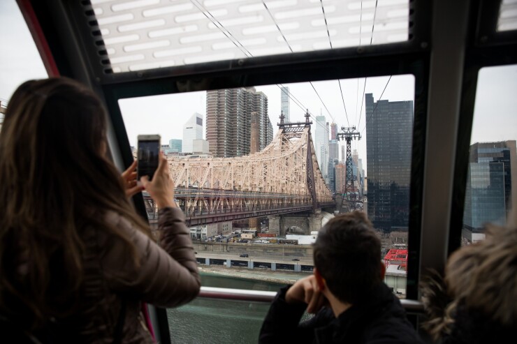 A person takes a photo of the Ed Koch Queensboro Bridge while riding the Roosevelt Island tram in New York.