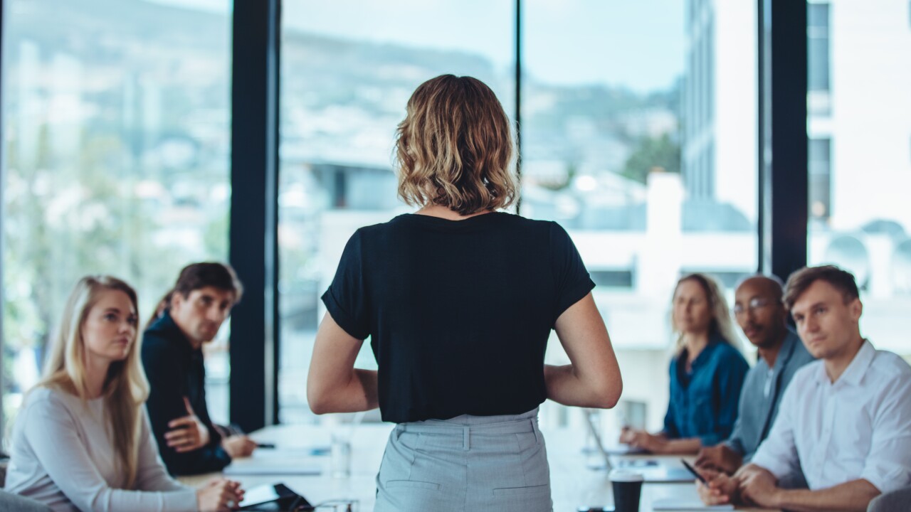 Woman standing in front of a group of people making an announcement