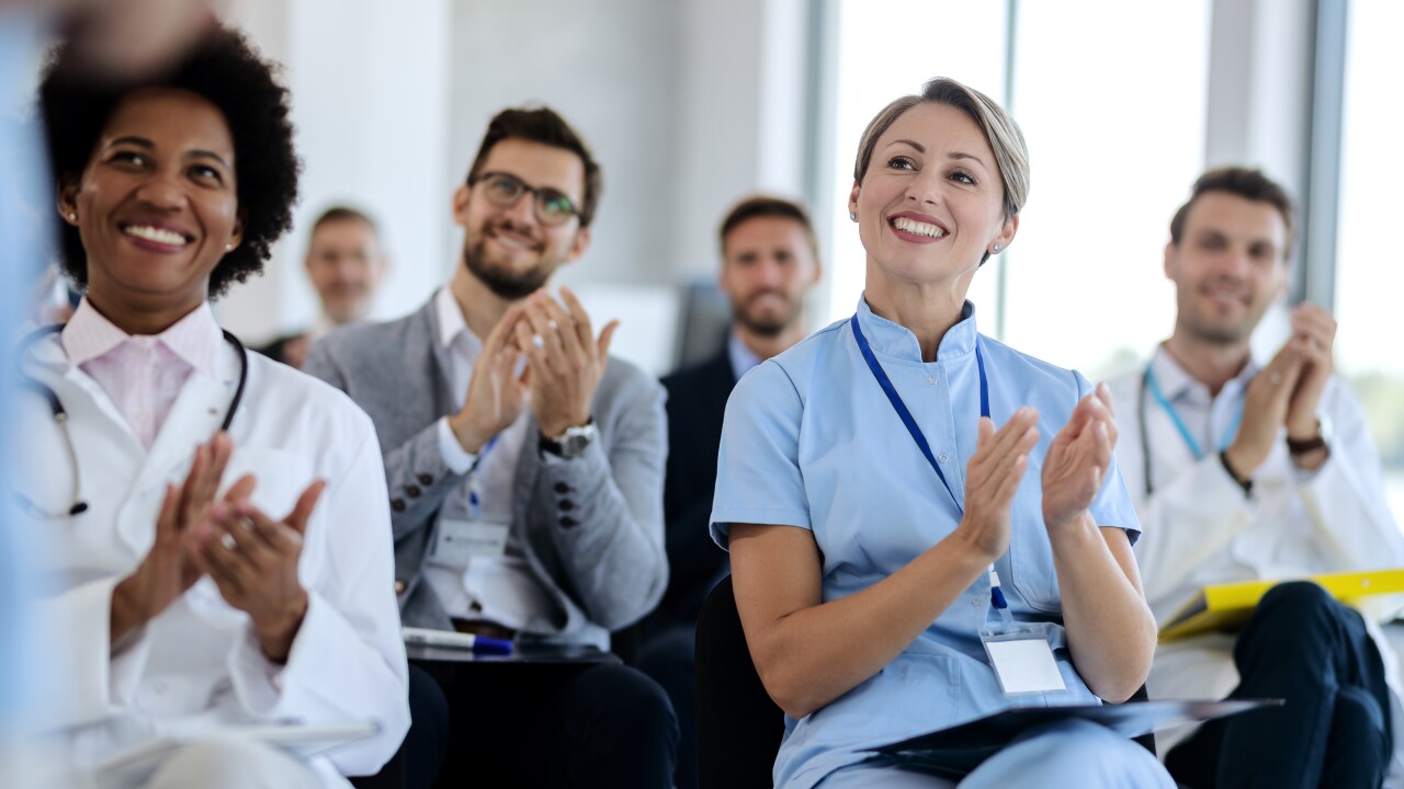 Medical professionals sitting in chairs clapping
