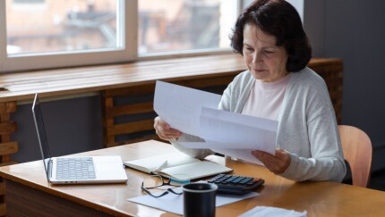 Older woman looking at paperwork, sitting at desk