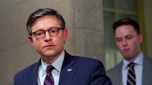 House Speaker Mike Johnson walking and carrying a folder