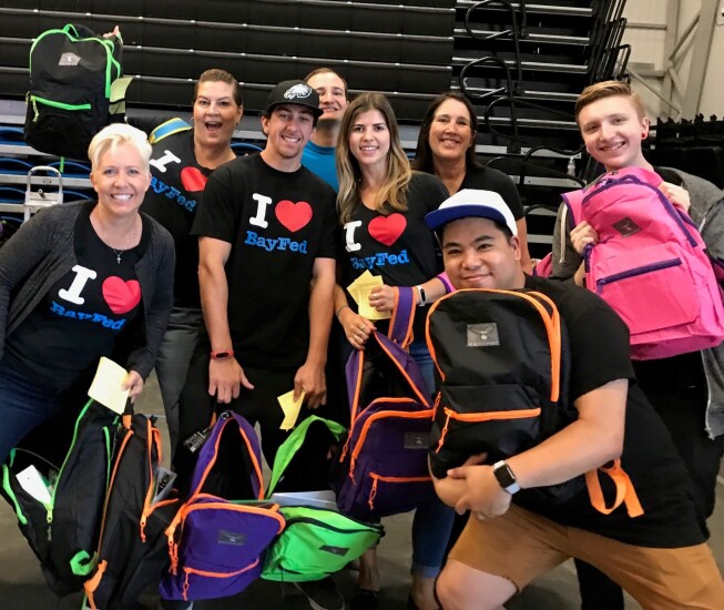 In Capitola, Calif., Bay Federal Credit Union’s CEO Carrie Birkhofer (top row, far right) poses with employees at a United Way “Stuff the Bus” back to school backpack drive for homeless youth.