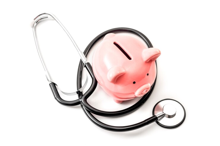 A pink piggy bank wrapped in a stethoscope