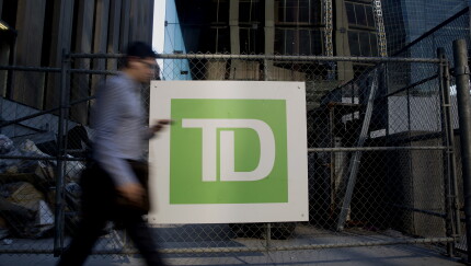 A commuter walks past Toronto-Dominion Bank signage in the financial district of Toronto.