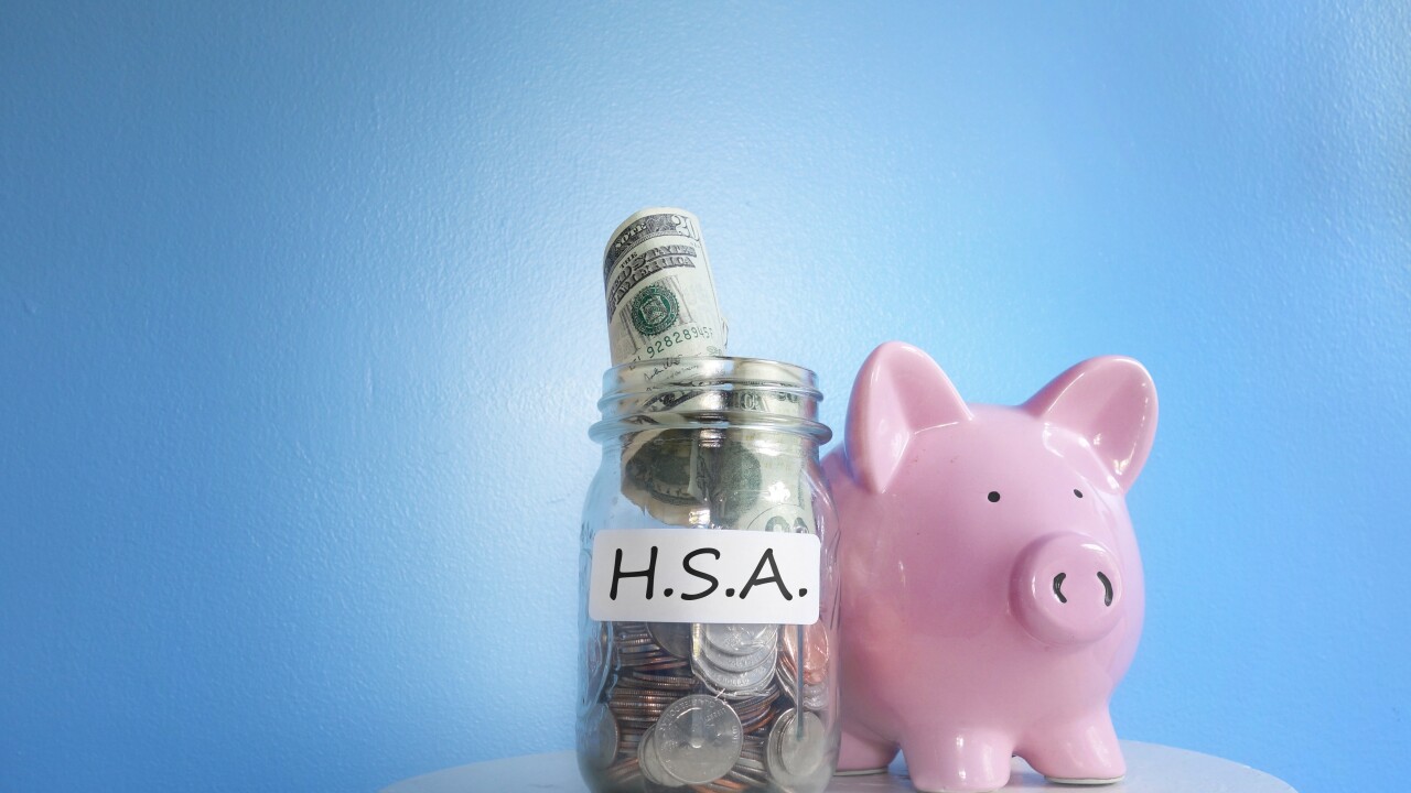 A piggy bank sits on a table next to a mason jar with bills and coins labeled 'H.S.A.'
