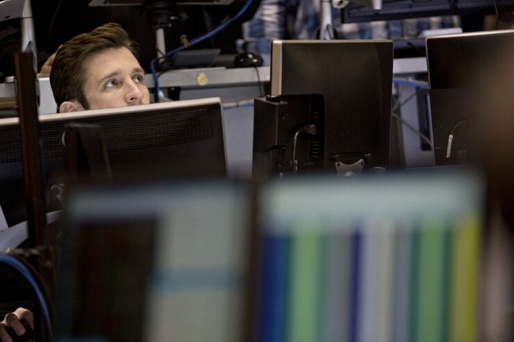 The head of a male figure peeks out above a series of computer monitors.