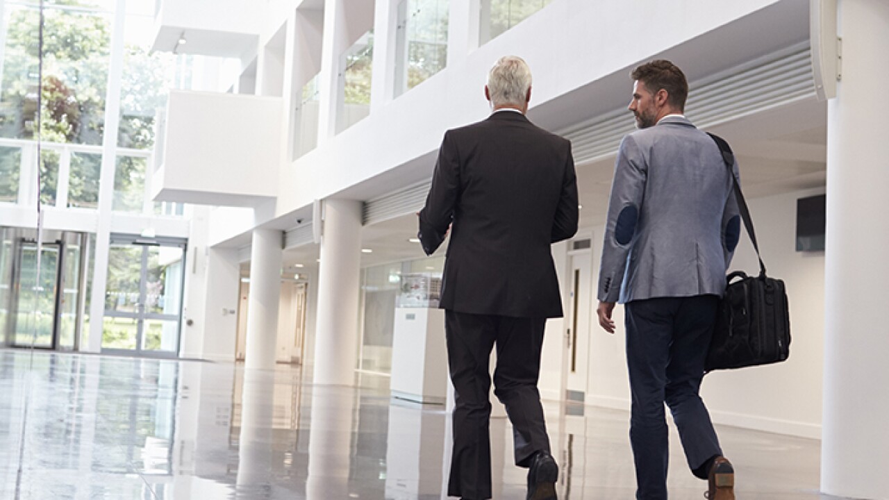 Businessmen walking through an office lobby.