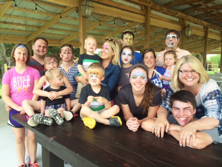 Staff and family at Allen, Gibbs & Houlik enjoy face painting at a family picnic